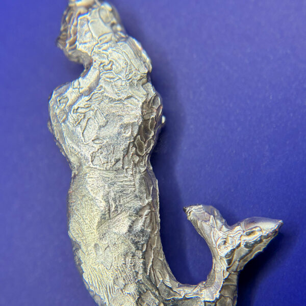 Close-up of silver mermaid pendant showing textured surface