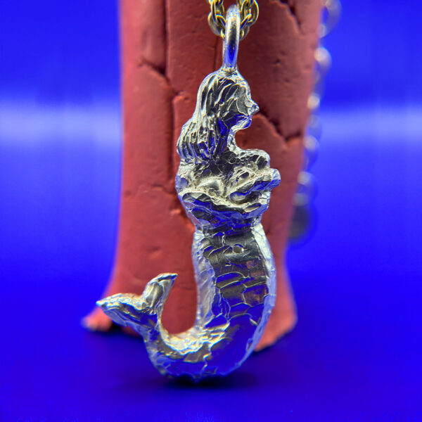Silver mermaid pendant on neutral background